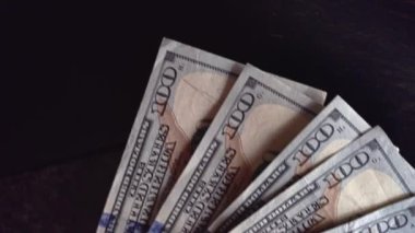 Milan, İtalya 1 Ocak 2025: Koyu ahşap bir yüzeye 100 dolarlık banknotlar serildi