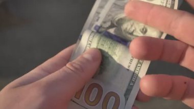 Milan, İtalya 1 Ocak 2025: İşadamı 100 dolarlık banknotları sayıyor