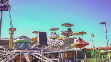 Rovigo, İtalya 1 Ocak 2025: Çocuklu aileler, antika bir eğlence parkında renkli dönen uzay gemilerine binerek güneşli bir günün tadını çıkarıyorlar