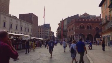 Verona, İtalya 1 Ocak 2025: Adam Verona, İtalya 'daki Piazza delle erbe' de yürüyor, turist ve yerlilerin yanından geçiyor