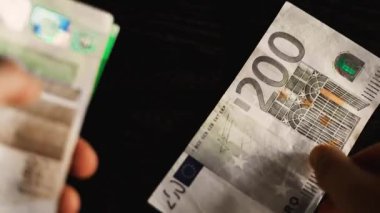 Milan, İtalya 1 Ocak 2025: Kasiyer siyah bir masa üzerindeki avro banknotlarını sayıyor