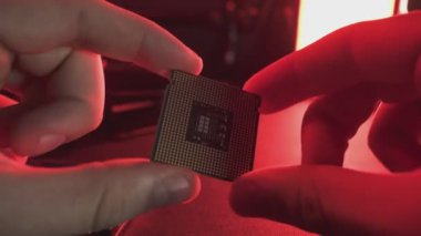 Milan, İtalya 1 Ocak 2025: Teknisyen dikkatle kırmızı ışıkta bir işlemci mikroçipi tutuyor ve inceliyor