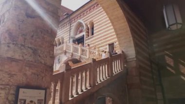 Verona, İtalya 1 Ocak 2025: Turistler, İtalya 'nın Verona kentindeki tarihi bir binanın balkonundan güneş gökyüzünde parlarken ve hareket ederken çevreyi gözlemliyorlar