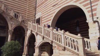 Verona, İtalya 1 Ocak 2025: İtalya 'nın Verona kentinde bulunan Verona della ragione sarayının avlusunu gezen turistler, belirgin çizgili desenleri ve yakınlardaki torre dei lamberti
