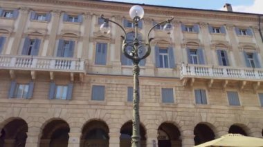 Verona, İtalya 1 Ocak 2025: Kamera yukarı doğru hareket ediyor, İtalya 'nın Verona kentindeki bir meydanın renkli binalarını ve büyüleyici mimarisini gözler önüne seriyor