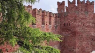 Verona, İtalya 1 Ocak 2025: Şatonun görkemli tuğla duvarlarını ve siperlerini ele geçirmek, İtalya 'nın Verona kentindeki yemyeşil sularla çevrili tarihi mimariyi gözler önüne sermek