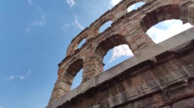 Verona, İtalya 1 Ocak 2025: Kamera İtalya 'da verona arenasının kemerlerini yukarıdaki parlak mavi gökyüzü ile yukarı doğru gösteriyor