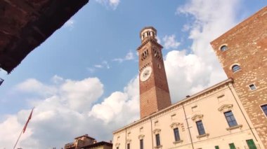 Verona, İtalya 1 Ocak 2025: Kamera, tüm ihtişamıyla Torre dei Lamberti 'yi gözler önüne sererek, mavi gökyüzü ve kabarık bulutlara karşı çekilmiştir.