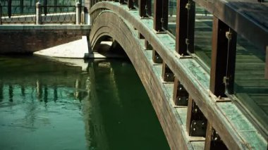 Treviso, İtalya 1 Ocak 2025: Güneş ışığı Treviso, İtalya 'da bir su yolu üzerindeki ahşap bir köprüyü aydınlatıyor