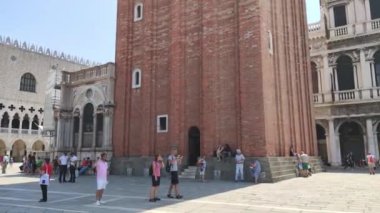 Venedik, İtalya 1 Ocak 2025: Turistler ve güvercinler arka planda büyük bir kamuflaj bulunan San Marco meydanında yerleşim halindeler.