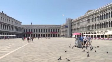 Venedik, İtalya 1 Ocak 2025: Venedik, İtalya 'da San Marco Meydanı' nda güneşli bir yaz gününde arka planda Basilica San Marco ile yürüyen turistler