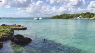 Bayahibe, Dominik Cumhuriyeti 1 Ocak 2025: Turkuaz su dalgaların üzerinde hafifçe sallanan teknelerle tropik bir plajda tur atıyor