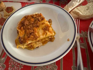 Ekmek ve aperatiflerle birlikte beyaz ve mavi bir tabakta duran bolonez, sıcak ve davetkar bir yemek sahnesi oluşturuyor.