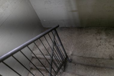 Beton merdiven loş bir bodruma iniyor, metal parmaklıklar var, gizem hissi uyandırıyor ve gölgeli, kumlu atmosferinde kentsel keşiflere davetiye çıkarıyor.