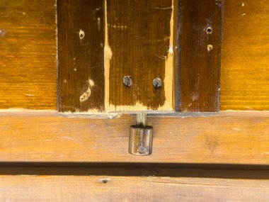 Ahşap kapı mandalının yakın plan görüntüsü, geleneksel işçiliğin doğasında olan eski ahşap tahılın ve kırsal çekiciliğin karmaşık detaylarını vurguluyor.