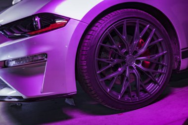 Roma, İtalya 02 Ocak 2025: modern bir spor arabanın stili ve lastiği, parlak pembe neon ışıkla aydınlatılmış, çarpıcı bir görsel yaratıyor.