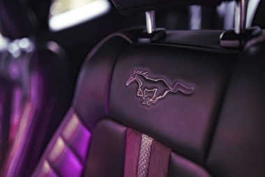 Rome, italy 02 january 2025: the iconic mustang horse is displayed on a stylish car seat, illuminated by ambient purple lighting, creating a luxurious atmosphere clipart