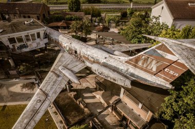 Rusted airplane integrated into a unique urban environment surrounded by greenery clipart