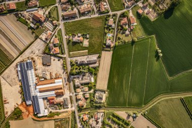 Fabrika çatılarında güneş panelleri olan küçük bir kasabanın hava manzarası sürdürülebilir enerji ve kırsal kesimi gösteriyor.