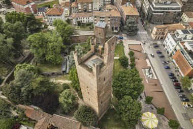 Torre di porta Castello 'nun hava perspektifi, Alessandria, İtalya' da yeşil alanlar ve kentsel gelişim ile çevrili bir ortaçağ kulesi.