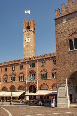 Treviso, İtalya 1 Ocak 2025: Piazza dei signori 'de güneşli bir günün tadını çıkaran turistler Treviso, İtalya' da Palazzo dei trecento ve onun sivil kulesi ile birlikte