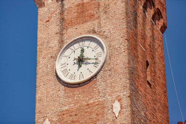 Treviso, İtalya 1 Ocak 2025: Güneşli bir günde, İtalya 'nın Treviso kentindeki tuğla bir kulede beyaz saat, Roma rakamlarıyla karşılaşıyor.