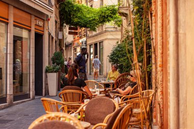 Treviso, İtalya 1 Ocak 2025: İnsanlar Treviso, İtalya 'da bir yaz öğleden sonrasında hasır koltuklarda oturur, içer ve sohbet ederler.