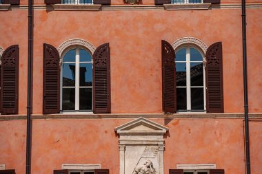 Verona, İtalya 1 Ocak 2025: Geleneksel İtalyan mimarisi, kemerli pencereler, açık panjurlar ve Verona 'daki bir terasotta cephesinde büyük bir rahatlama sergiliyor