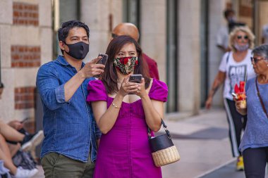 Verona, İtalya 1 Ocak 2025: Koruyucu yüz maskesi takan turistler covid-19 salgını sırasında İtalya 'nın Verona kentinde akıllı telefonlarını kullanıyorlar