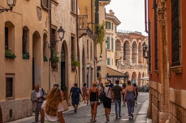 Verona, İtalya 1 Ocak 2025: İtalya 'da mazzini üzerinden yürüyen turistler, İtalya' nın Verona şehrinde bir Roma amfitiyatrosu olan arenada, sokağın sonundan görülüyor.