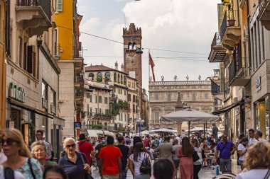 Verona, Italy 1 January 2025: Tourists walking on via mazzini, a famous shopping street in the historic center of verona, italy, with the torre dei lamberti in the background clipart