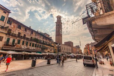 Verona, İtalya 1 Ocak 2025: Verona, İtalya 'da turistler Verona, İtalya' da turistik alanlarda gezinirken, Torre dei Lamberti pazar tezgahlarının üzerinde yükseliyor