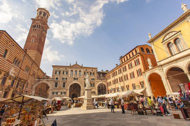 Verona, İtalya 1 Ocak 2025: Güneşli bir günde arka planda lamberti kulesi bulunan İtalya 'nın Verona kentinde bulunan Piazza delle erbe' deki pazarı ziyaret eden turistler