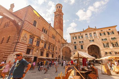 Verona, İtalya 1 Ocak 2025: Piazza delle erbe 'de yürüyen ve alışveriş yapan turistler ve Torre dei Lamberti arka planda, verona, İtalya