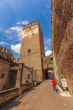 Verona, Italy 1 January 2025: Tourist walking under the arch of castelvecchio in verona, italy, enjoying the view of the medieval bridge clipart