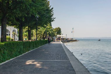 Garda Gölü, İtalya 3 Ocak 2025: Turistler Bardolino veya Lazise 'de Garda Gölü' nün pitoresk gezinti alanında güneşli bir günün tadını çıkarıyorlar