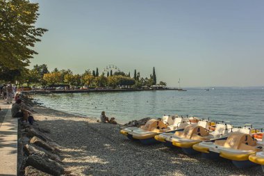 Garda Gölü, İtalya 3 Ocak 2025: Garda Gölü kıyısında pedal botları, güneşli günün tadını çıkaran turistlerle