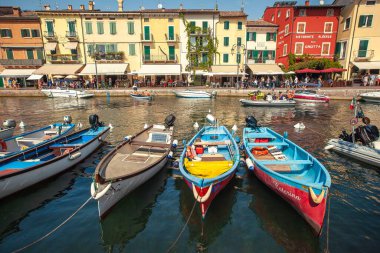Garda Gölü, İtalya 3 Ocak 2025: Tembel limanına demirlemiş renkli ahşap botlar. Garda Gölü 'nün güneydoğu kıyısında büyüleyici bir kasaba. İtalya