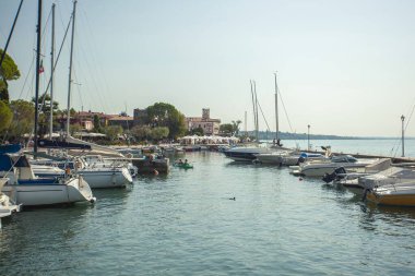 Garda Gölü, İtalya 3 Ocak 2025: Bardolino 'daki pitoresk limanın manzarası, Garda Gölü kıyısında yelkenli ve motorlu teknelerin yer aldığı büyüleyici bir kasaba