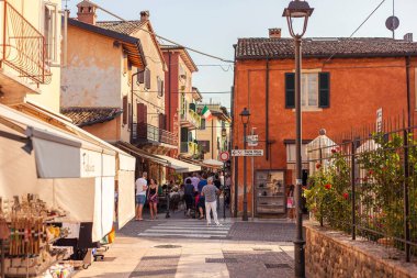 Garda Gölü, İtalya 3 Ocak 2025: İnsanlar güneşli bir yaz gününün keyfini çıkarıyorlar Bardolino 'da yürüyüş ve alışveriş yapıyorlar, Garda Gölü üzerindeki pitoresk kasaba, İtalya' nın ünlü turizm beldesi