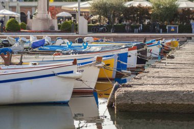 Garda Gölü, İtalya 3 Ocak 2025: Limanda demirlemiş renkli ahşap botlar Bardolino, İtalya 'daki Garda Gölü' nün sakin sularını yansıtıyor