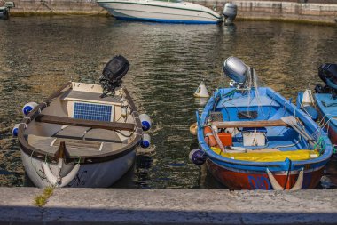 Garda Lake, Italy 3 January 2025: Two colorful fishing boats with outboard motors and fishing nets are moored at the stone dock on lake garda in italy clipart