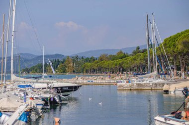 Garda Gölü, İtalya 3 Ocak 2025: Yelkenliler ve motorbotlar güneşli bir yaz gününde Bardolino, Garda Gölü, İtalya 'ya yanaşıyor