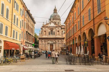 Modena, İtalya 1 Ocak 2025: Modena şehir merkezinde arka planda Aziz George Kilisesi ile yürüyen yaşlı çift, Emilia Romagna, İtalya