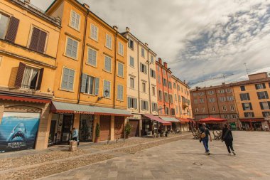 Modena, İtalya 1 Ocak 2025: Piazza della pomposa, modena, İtalya 'da renkli binalar ve dükkanlarla yürüyen iki turist