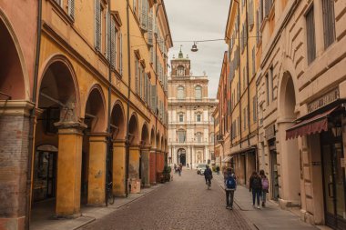 Modena, İtalya 1 Ocak 2025: Arka planda palazzo ducale ile tipik bir modena caddesinde yürüyen öğrenciler
