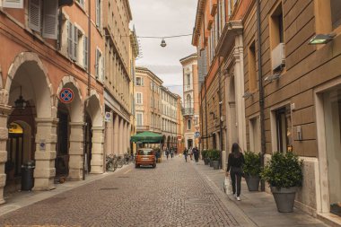 Modena, İtalya 1 Ocak 2025: İtalya 'nın tarihi şehir merkezi Modena' da renkli binalar ve saksı bitkileriyle dolu bir kaldırım taşı caddesinde yürüyen alışverişçi