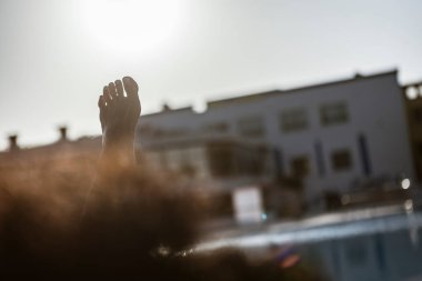 Güneş ışığı ön planda, Marsa Alam, Mısır 'da bulanık bir havuz kenarı tatil köyü, parlak bir gökyüzü altında huzurlu bir tatil havası yakalıyor.