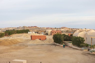 İnşaat malzemeleri ve çöl manzarası, Marsa alam, Mısır 'da bir çöl bölgesindeki kentsel gelişimi ön plana çıkaran bir inşaat alanını karakterize etmektedir.