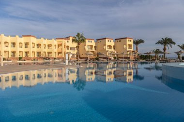 Huzurlu mavi yüzme havuzu Marsa Alam, Mısır 'da lüks bir oteli yansıtıyor. Huzurlu ve davetkar bir tatil atmosferi yaratıyor.